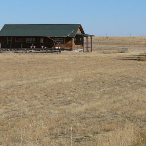 Small wooden home surrounded by a large open field