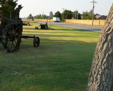 A large lawn with old farm equipment on it